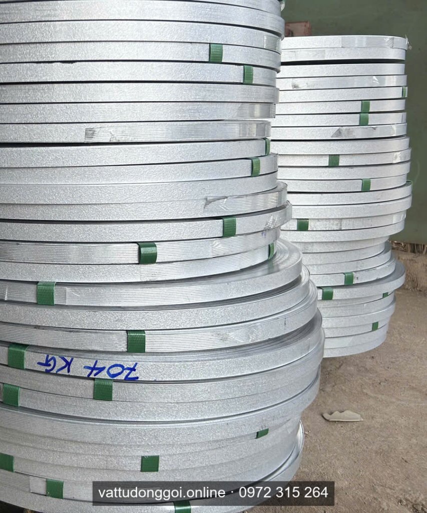 Chồng cuộn đai thép mạ kẽm bên phải trong kho, bề mặt sáng đều