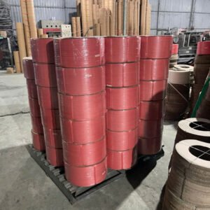 Cuộn dây đai màu đỏ xếp chồng trên pallet nhựa trong xưởng