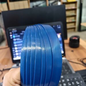 Cuộn dây đai nhựa PET màu xanh dương trên tay, bề mặt dập vân