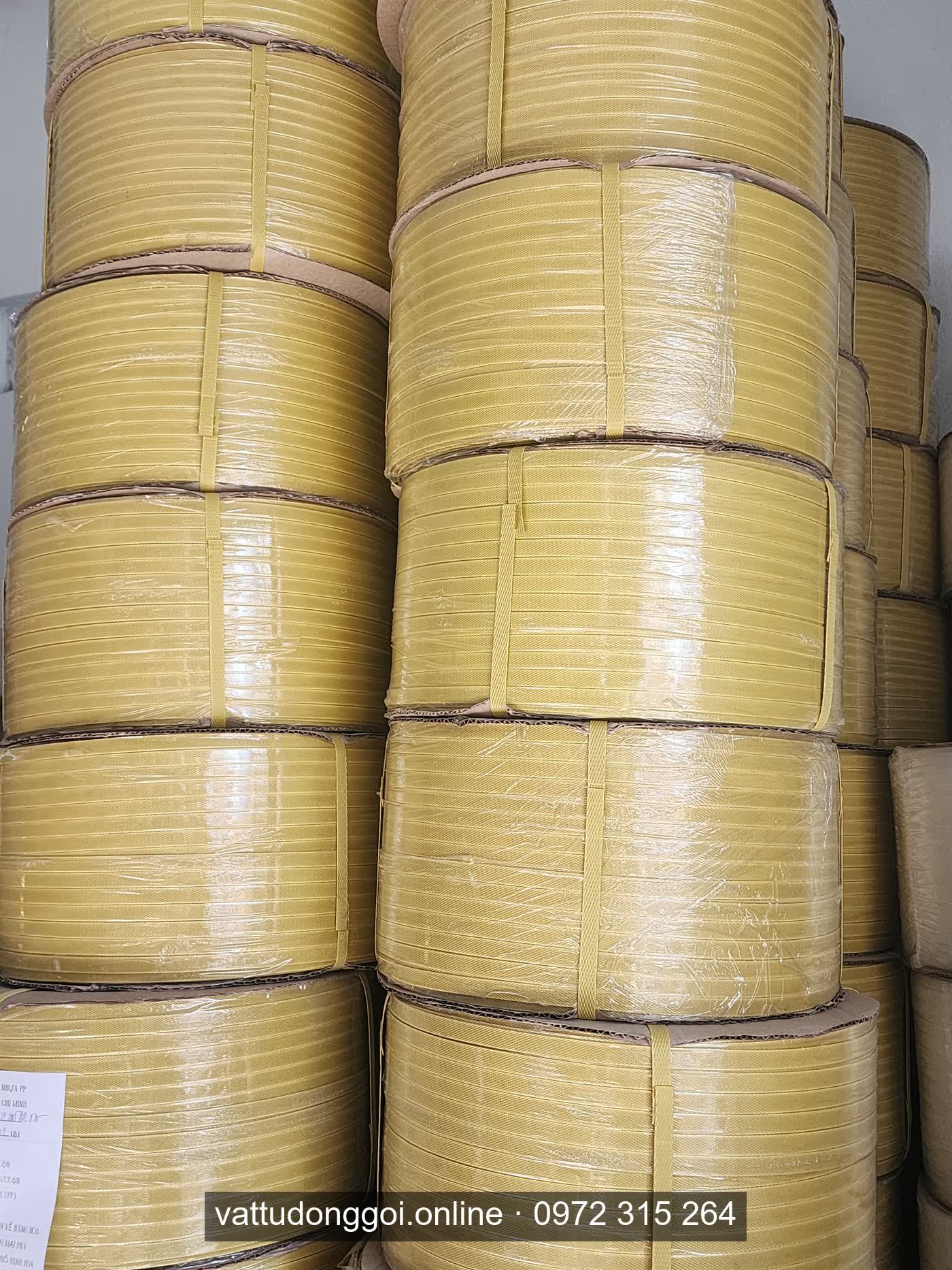 Cuộn dây đai PP màu vàng xếp thành cột trong kho