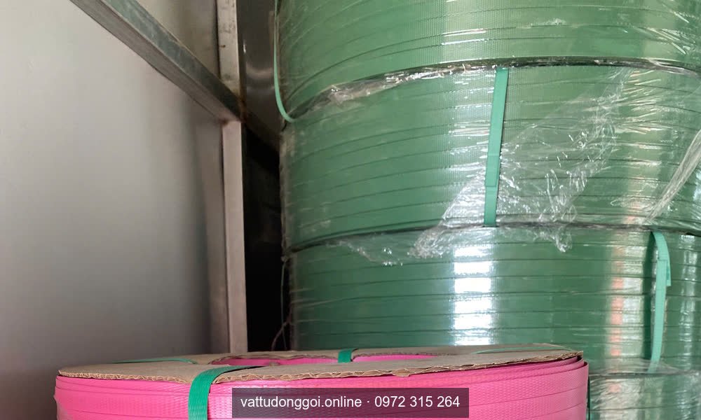 Cuộn dây đai nhựa màu xanh lá xếp phía sau cuộn màu hồng trong kho