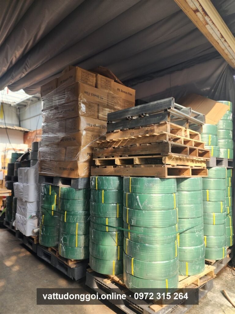 Dây đai PET xanh lá xếp trên pallet gỗ cạnh thùng carton trong kho Đỉnh Phong 68