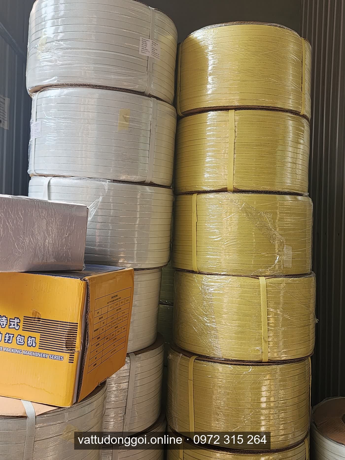 Cuộn dây đai PP màu trắng và vàng xếp chồng trong kho