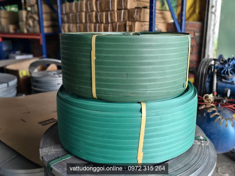 Hai cuộn dây đai nhựa PET màu xanh lá xếp chồng, có băng keo vàng giữ cuộn