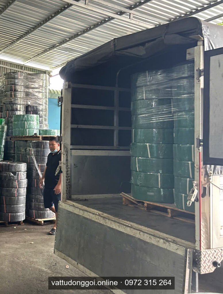 Xe tải mở thùng cạnh các cuộn dây đai xanh lá chuẩn bị nhận hàng xuất khẩu